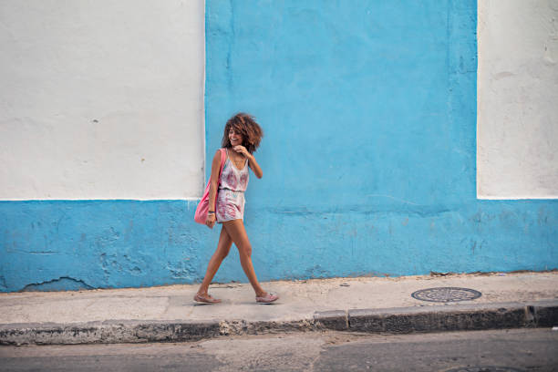 Happy woman looking away on sidewalk against wall