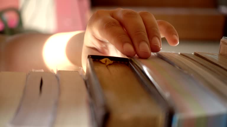 Woman hand finding a book on bookshelf in the library