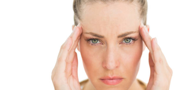 istock Woman with headache touching her temples frowning at camera 690246108