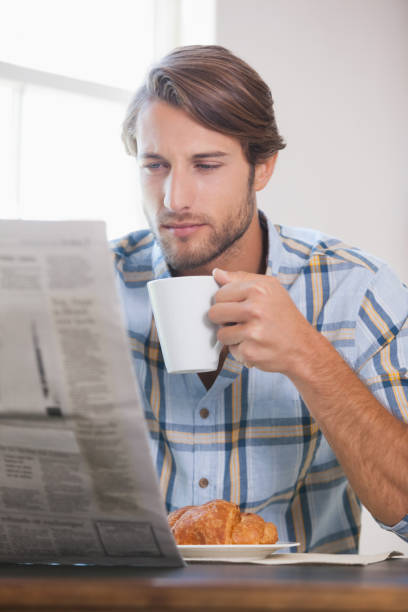 istock Handsome man drinking coffee and reading newspaper 690251232