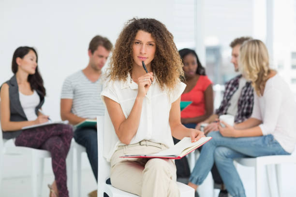 istock Focused woman looking at camera while colleagues are talking behind her 690251954