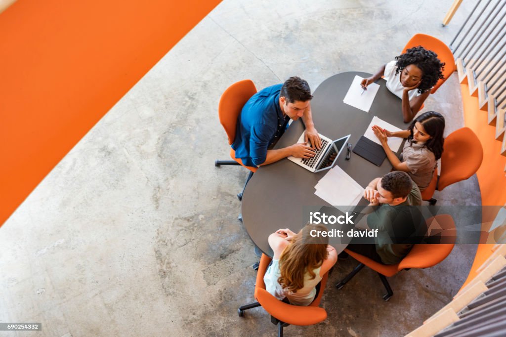 Top Down View of Open Plan Business Meeting Top down view of a group of young entrepreneurs working together in a start up business meeting High Angle View Stock Photo