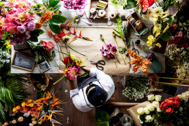 kwiaciarnia pracuje nad układaniem kwiatów wśród kwiatów - kwiaciarnia zdjęcia i obrazy z banku zdjęć