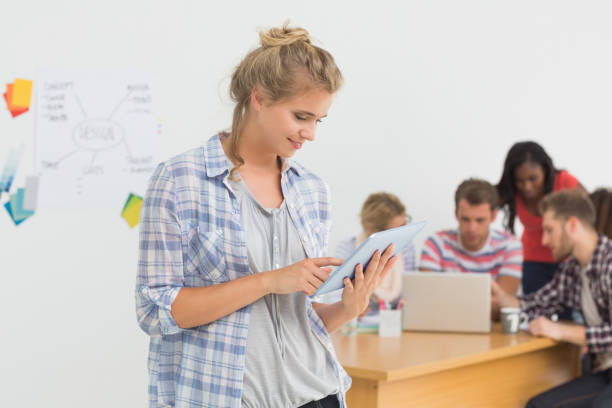istock Smiling young designer using her tablet in front of her colleagues 690259570