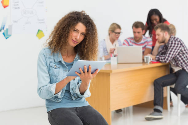 istock Happy designer sitting in front of her colleagues using digital tablet 690259602