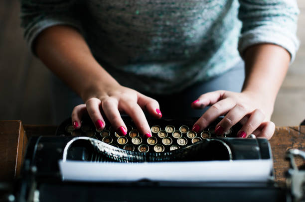 istock Woman typing vintage typewriter on wooden table 690259852