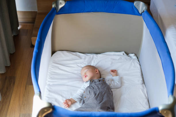 aziatische 1 jaar oude peuter baby jongen kind slapen in babybedje in de buurt van bed van de ouder in de slaapkamer - babybox stockfoto's en -beelden