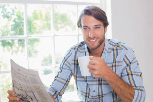 istock Casual smiling man having coffee while reading newspaper 690266000