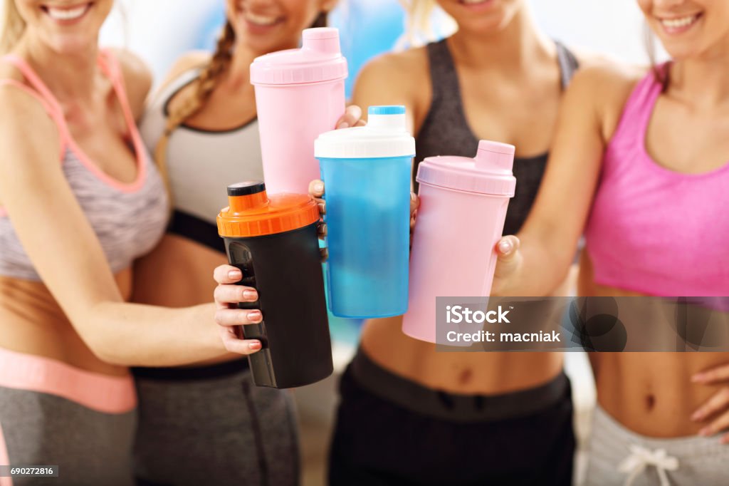Young women group resting at the gym after workout Picture showing young women group resting at the gym after workout Protein Drink Stock Photo