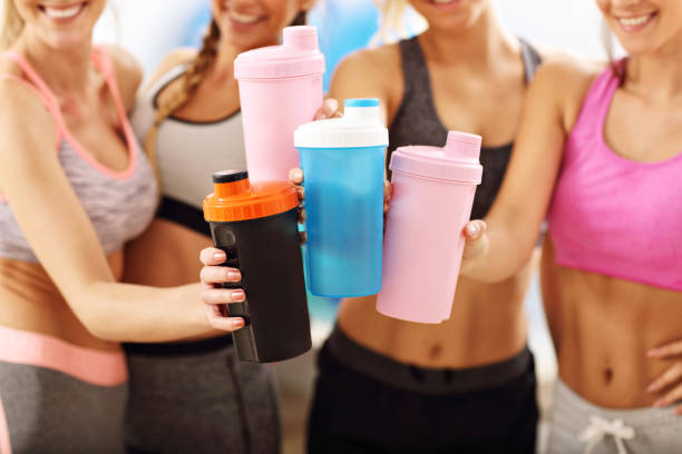Young women group resting at the gym after workout Picture showing young women group resting at the gym after workout protein drink stock pictures, royalty-free photos & images