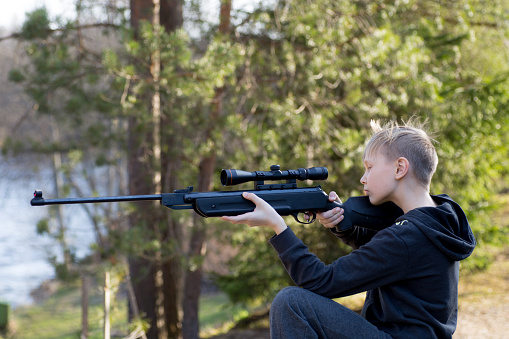 young teenager with air gun in forest