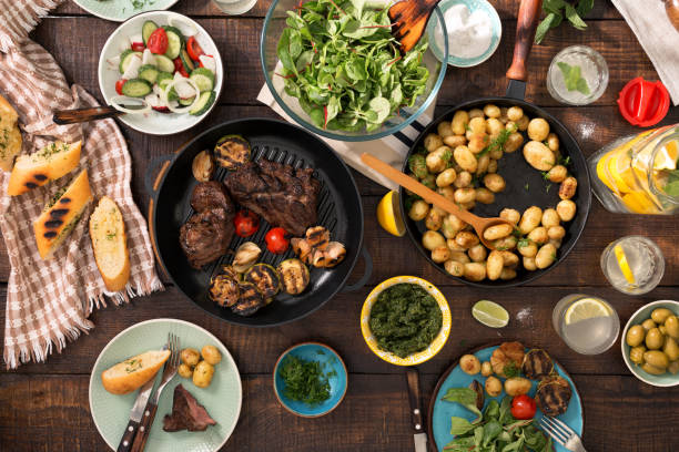 istock Dinner table with grilled steak, grilled vegetables, potatoes, salad, different snacks and homemade lemonade 690273896