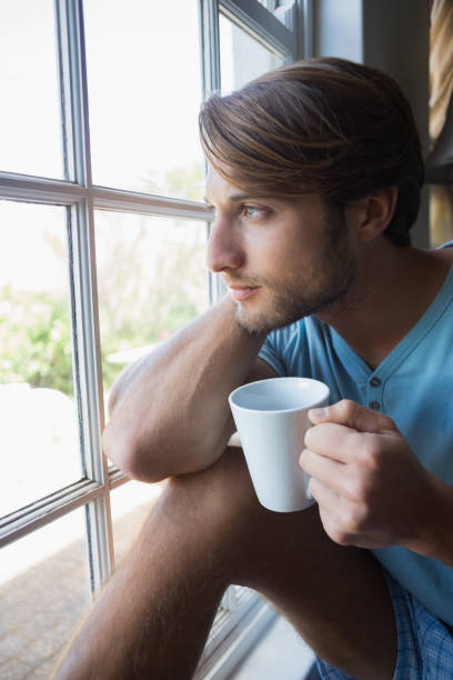 istock Thoughtful man sitting by the window having coffee 690274542