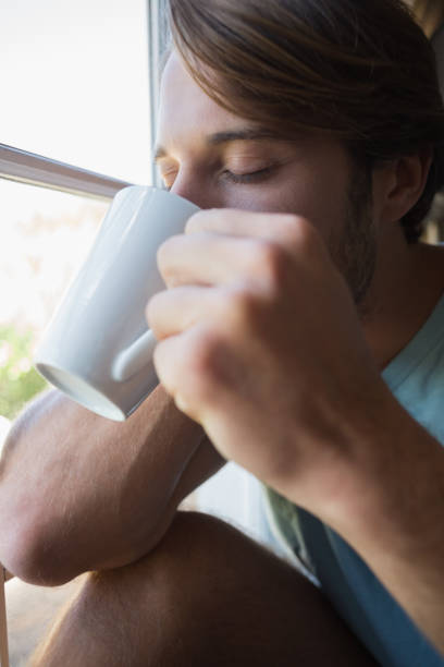istock Handsome man sitting by the window having coffee 690274580