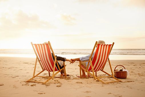 Shot of a senior couple relaxing together on chairs at the beach