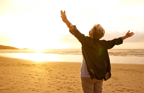 Embrace life with open arms Shot of a joyful senior woman with her arms outstretched at the beach arms outstretched stock pictures, royalty-free photos & images