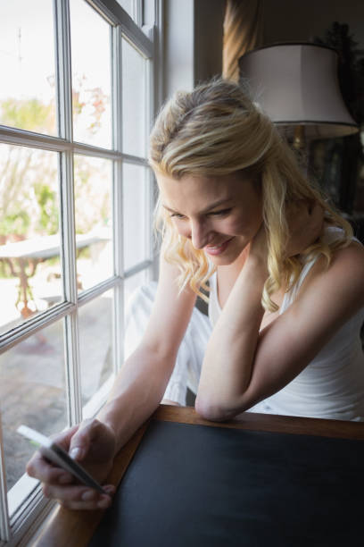 istock Pretty blonde sitting by the window sending a text 690288140