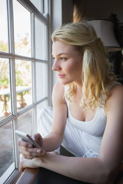 istock Pretty blonde sitting by the window sending a text 690288152