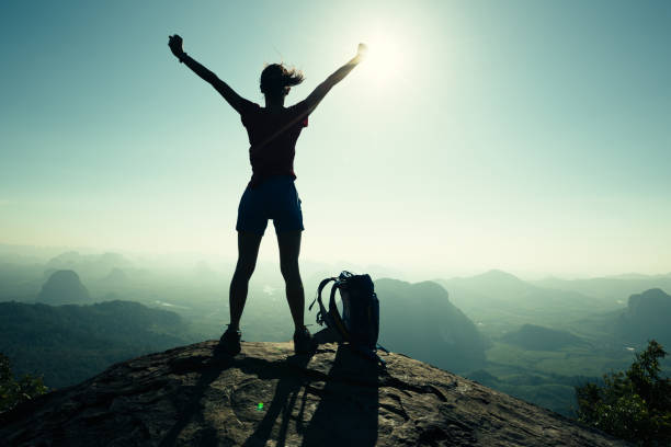 Photo of successful woman hiker open arms on sunrise mountain peak