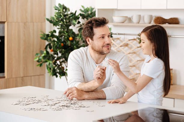 istock Father and daughter uniting two jigsaw puzzle pieces 690314818
