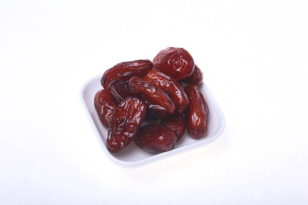 istock Delicious dried organic dates on bowl isolated over white background. 690319464
