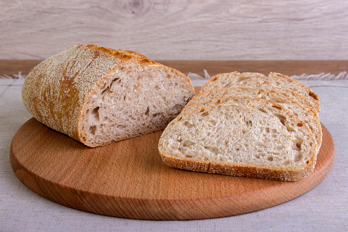 Baked loaf of baguette bread with beautiful crust, served on wooden board