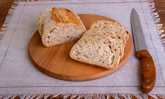 Fresh bread slice and cutting knife on rustic table