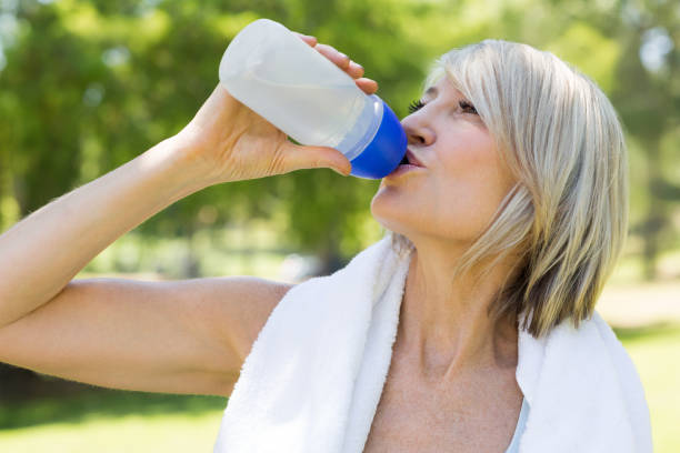 mulher bebendo água no parque - water bottle sports and fitness selective focus sport - fotografias e filmes do acervo