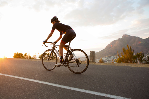 A young female cyclist is out on a training ride on his racing bike near Table Mountain, Cape Town