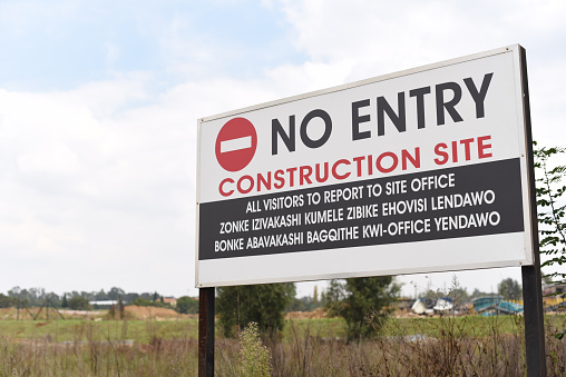A warning sign placed outside of a construction site, North of Johannesburg, South Africa near Waterfall Estate. Do not Enter signage. All visitors to report to site office. No Entry sign on construction site in South Africa, Johannesburg warning visitors to report to site office.