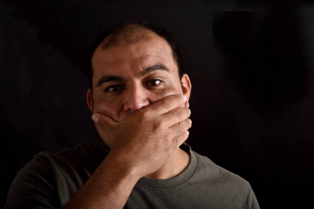 istock Man covering his mouth on black background 690342264