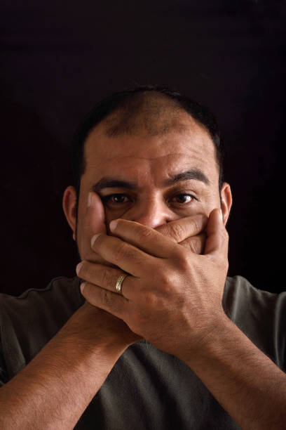 istock Man covering his mouth on black background 690342386