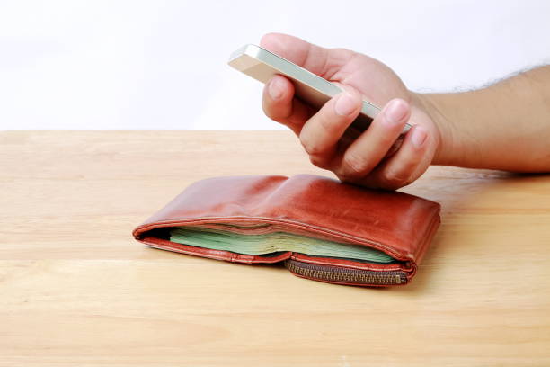 istock Men's Wallet and Mobile phone in hand on wood background. 690342584
