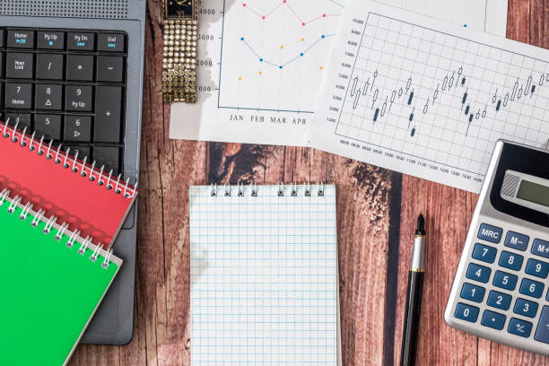 istock laptop, stock market data, with calculator and pen 690342598