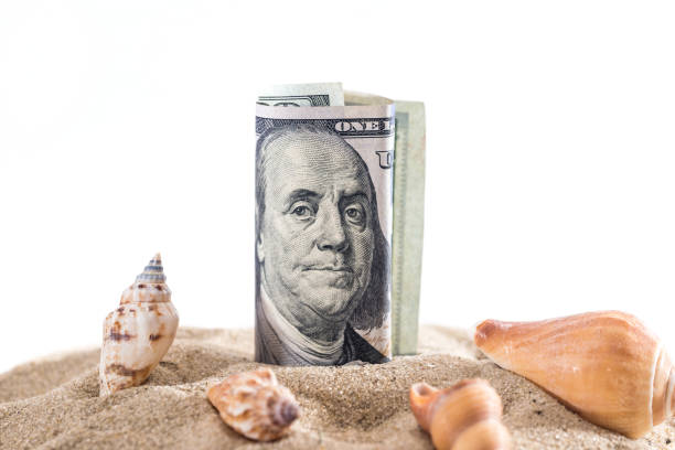 istock dollar in sand with shell isolated on white. summer concept 690343418