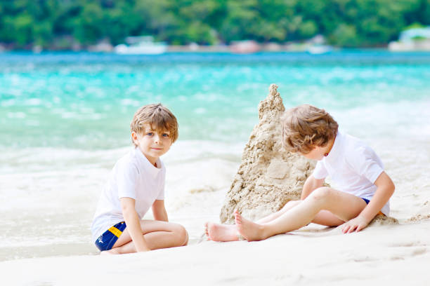 istock Two kid boys building sand castle on tropical beach 690351254