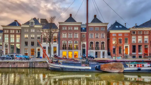 Old buildings on Hoge der Aa Quay with ship in Groningen city centre at sunset, Netherlands