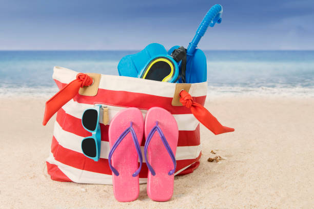 istock Woman bag with beach item on sand 690368342
