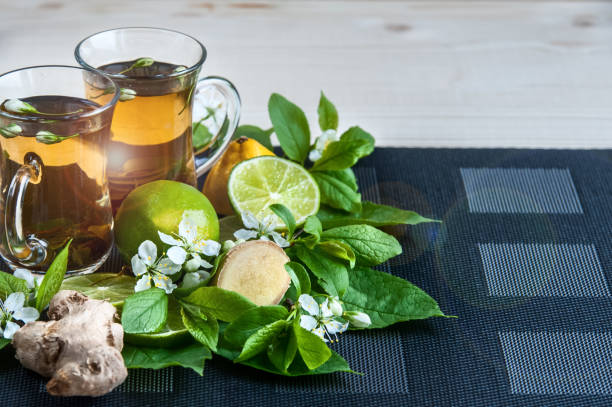 dois copos transparentes com chá. verde, preto, ervas, jasmine chá com limão e gengibre. tema do chá. de cozinha, chá de embalagem, produção de alimentos, hotelaria - mint tea lemon tea leaves glass - fotografias e filmes do acervo