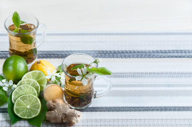 dois copos transparentes com chá. verde, preto, ervas, jasmine chá com limão e gengibre. tema do chá. de cozinha, chá de embalagem, produção de alimentos, hotelaria - mint tea lemon tea leaves glass - fotografias e filmes do acervo