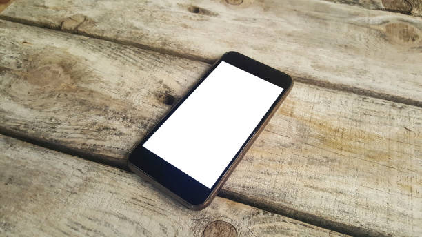 istock Smartphone with white screen propped on wooden bench 690390968