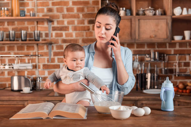 istock mother holding her son, talking on smartphone and preparing a dough 690396346