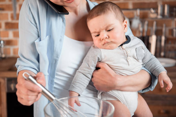 istock mother holding her son, talking on smartphone and mixing a dough 690396384