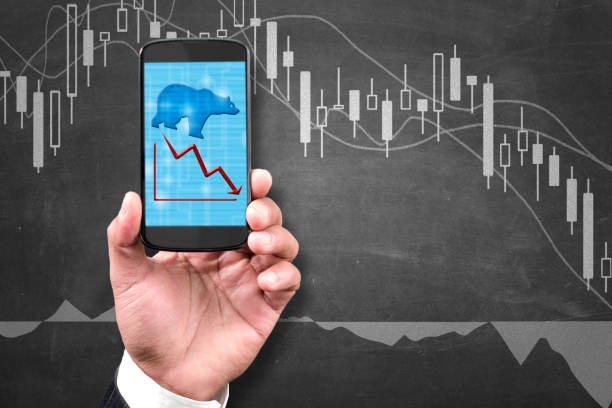 Bearish market Man holding smartphone with bearish trend indicating in blackboard in background trading stock pictures, royalty-free photos & images