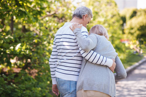 istock Helpful man helping senior wife in the park 690398050