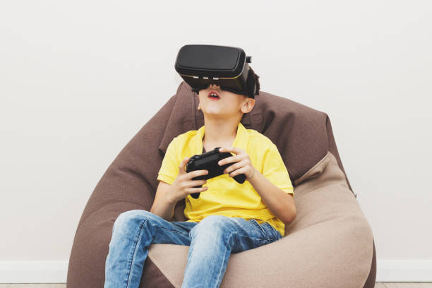 istock Boy plays game with virtual reality glasses indoors 690400488