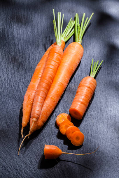 Organic carrots on black slate background