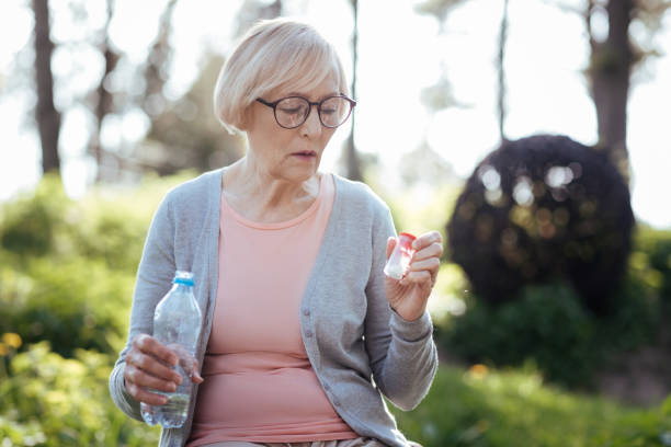 istock Attentive woman taking pills in the park 690404328