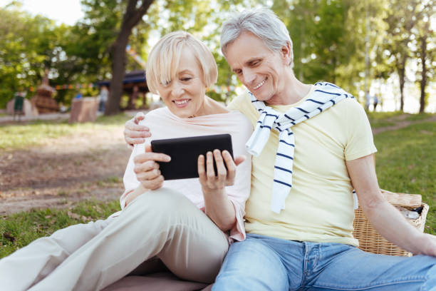 istock Happy pensioners using tablet in the park 690408660