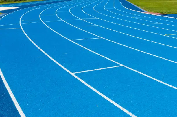Photo of Blue Running track .Lanes of blue running track.Running track with blue asphalt and white markings in outdoor stadium.selective focus.